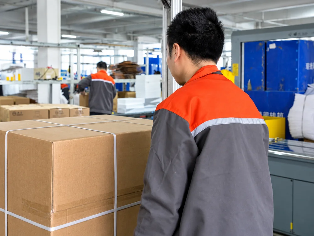 A worker beside a strapped carton in JINJIE's packing area