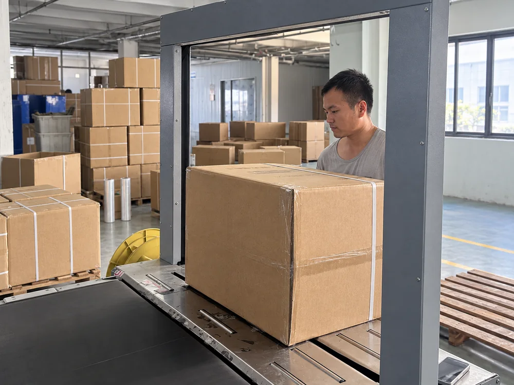 Worker and carton at the factory's strapping station