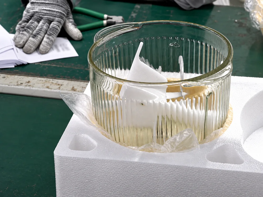 A glass bowl with protected contents on a foam insert at a JINJIE packing workstation