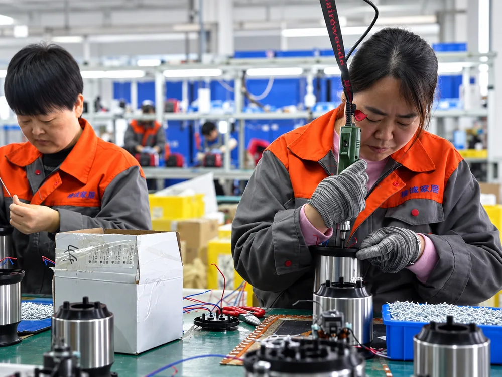 Workers handling motor housings at JINJIE assembly workstations