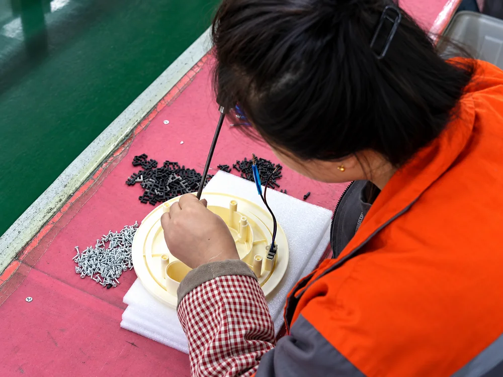 A worker assembling an appliance base at a JINJIE workbench