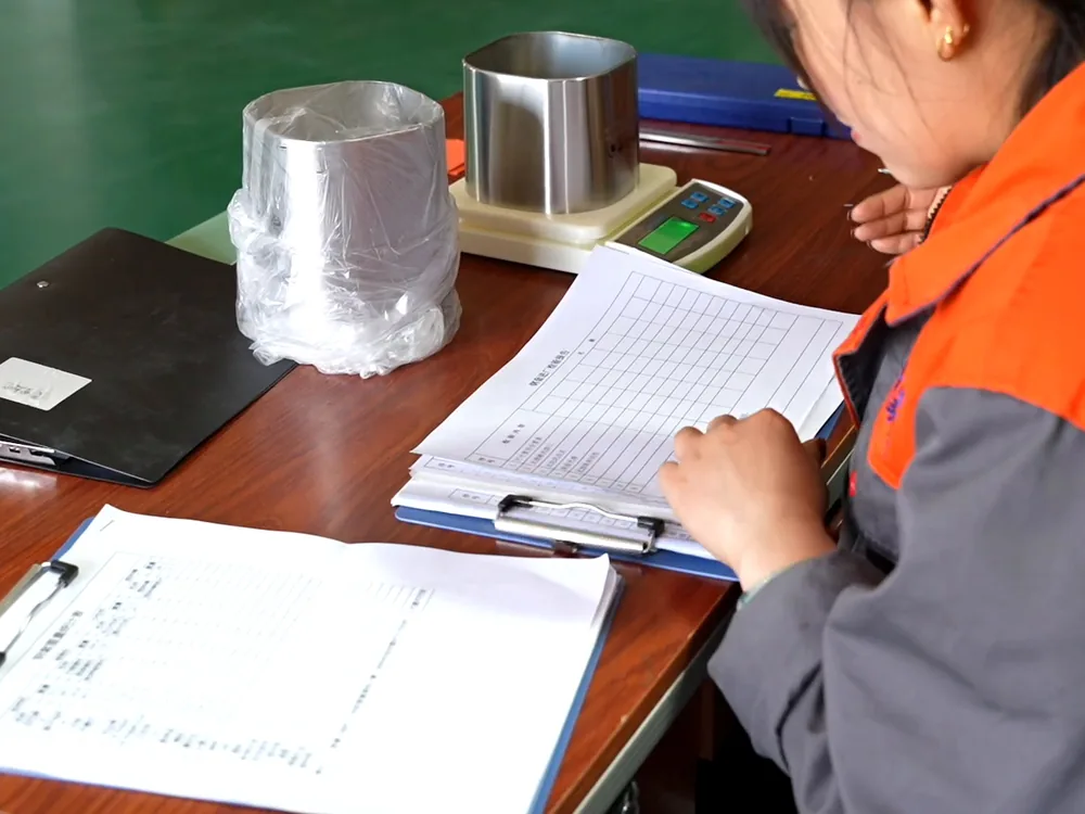 Metal components being weighed and recorded at the inspection desk.
