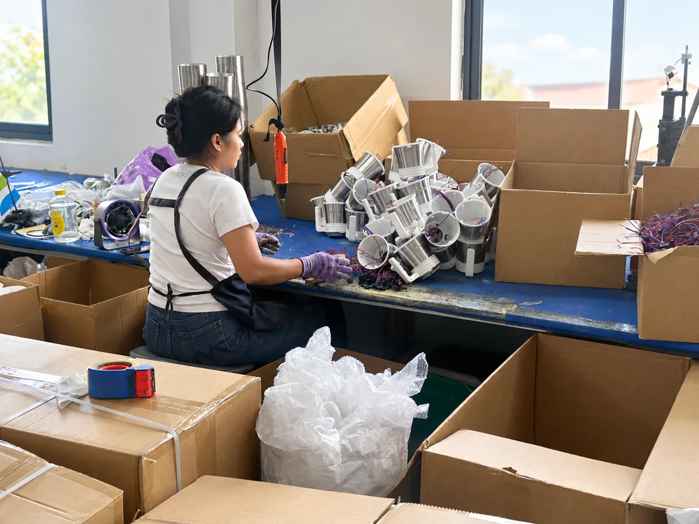 Worker assembling handled motor housings at a bench