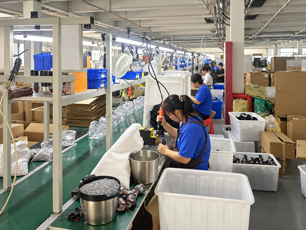 Workers assembling appliance components along a factory workbench