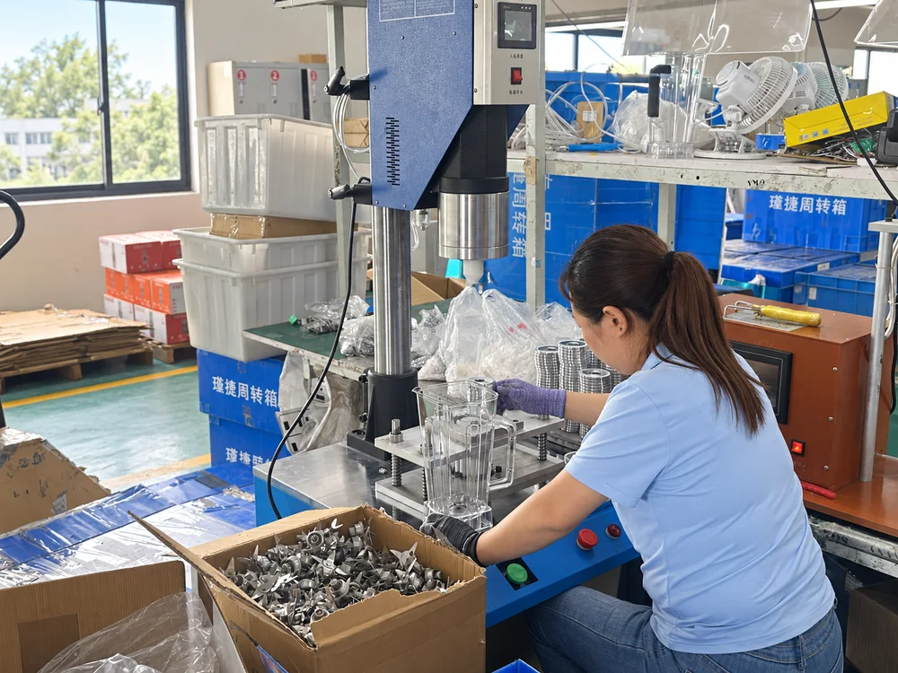 Worker handling a transparent blender jug at the actual assembly workstation