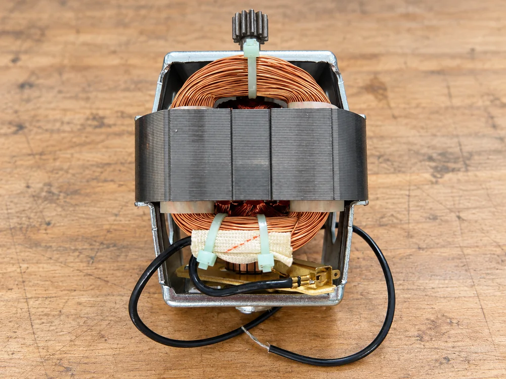 Loose appliance motor showing windings, terminals and drive gear