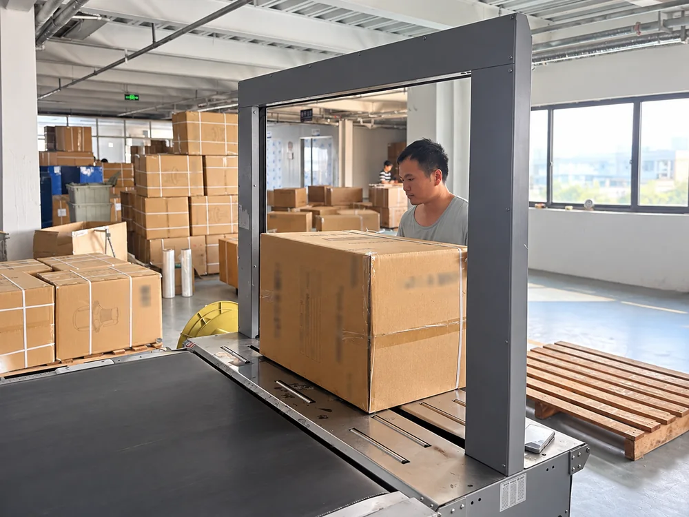 Actual worker behind a carton at the factory strapping conveyor with private markings blurred