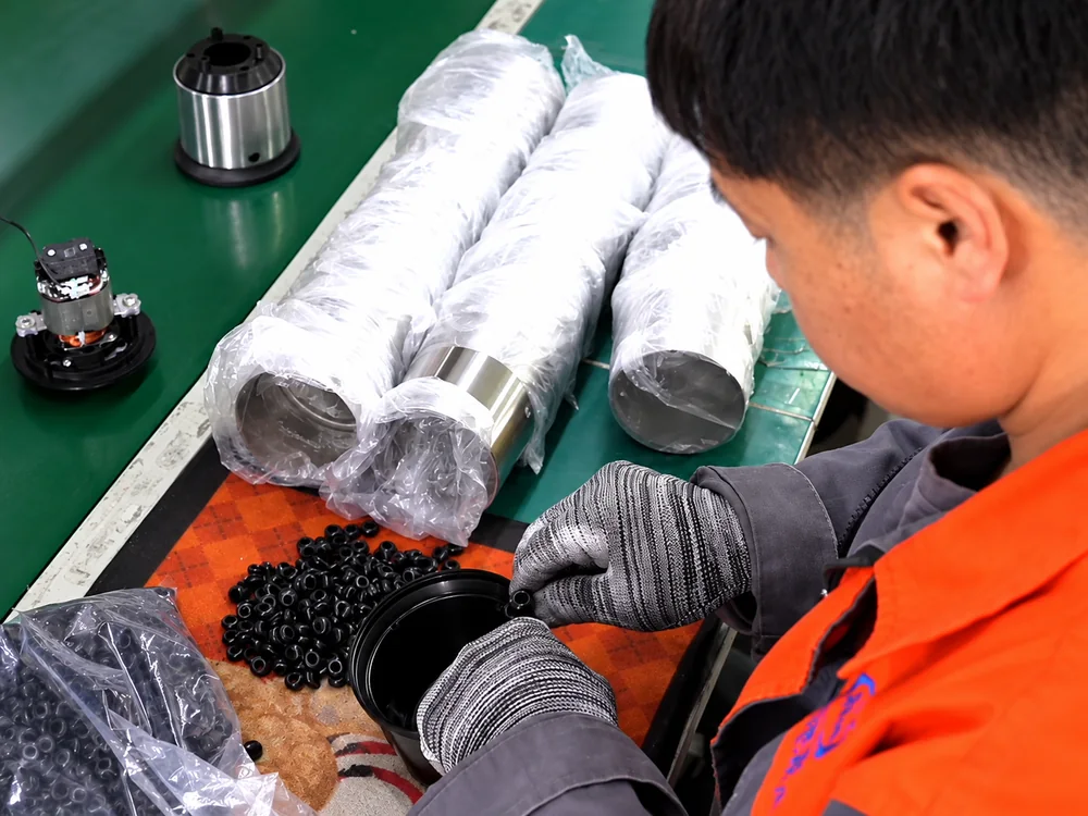 Gloved worker handling an appliance component beside protected metal housings
