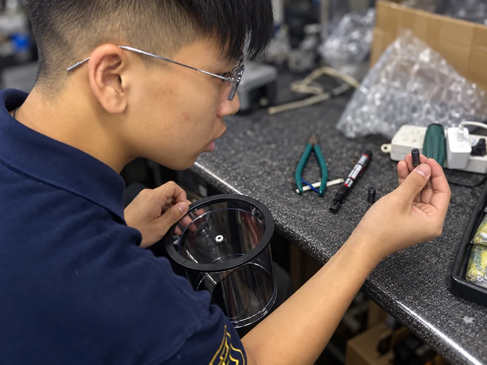 Technician at a real workbench examining a food chopper component and bowl